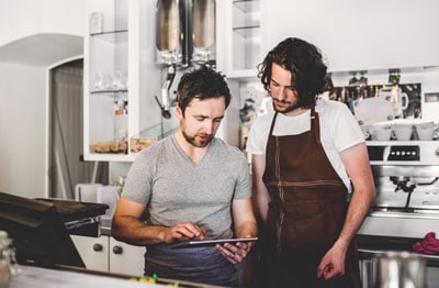 Coffee shop owner showing barista the staffing schedule.