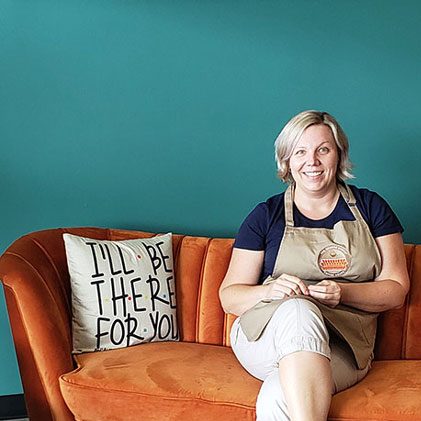 Owner of Orange Couch Coffee House sitting on the orange couch